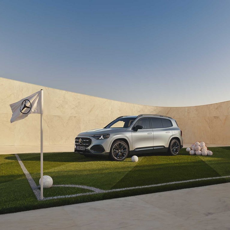 Silberner Mercedes-Benz GLB auf einem Golfplatz vor moderner Architektur mit Mercedes-Benz Fahne im Vordergrund. Das Motiv bewirbt die Mercedes-Benz Eintauschprämie bei S&G.