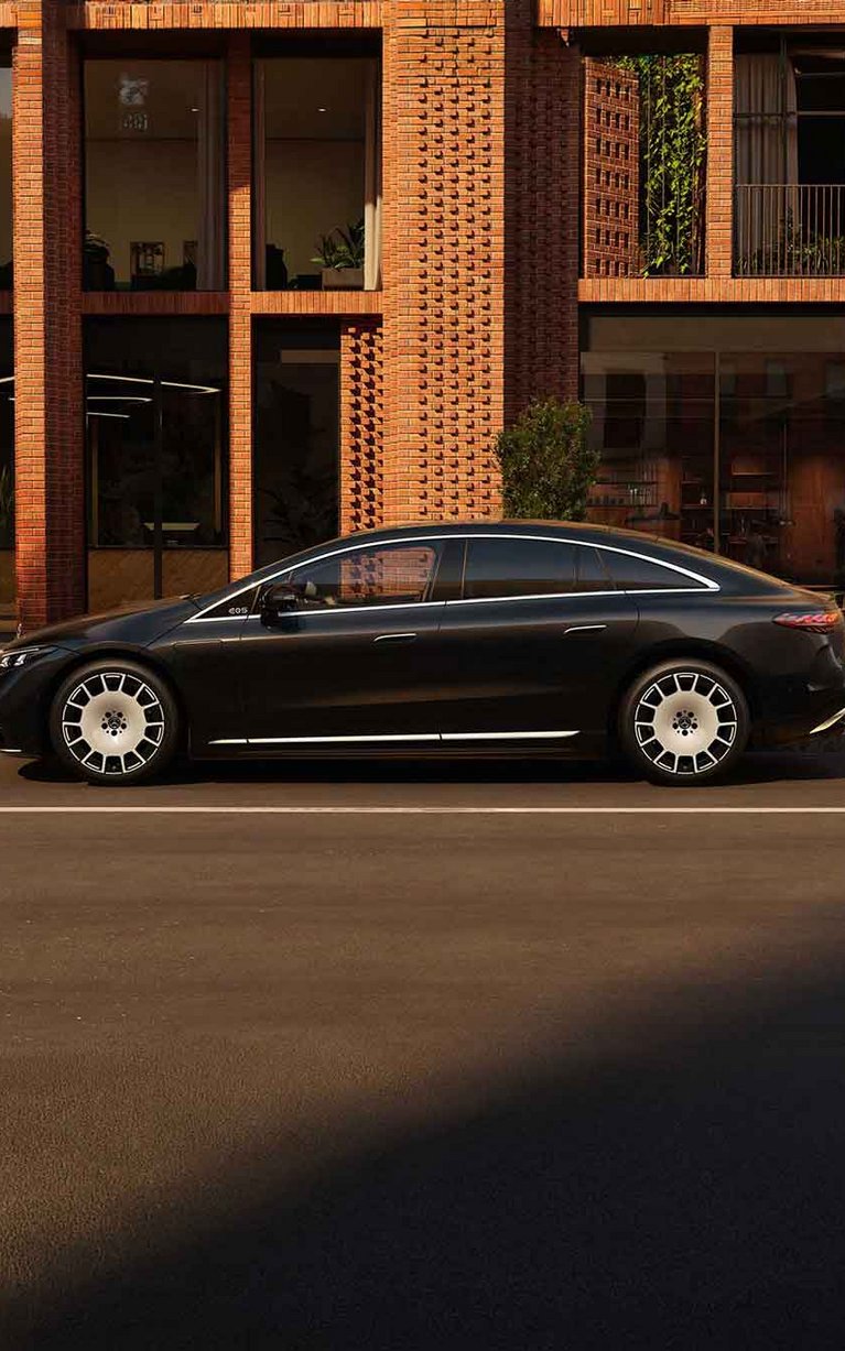Der neue Mercedes-Benz EQS seitenansicht, schwarz vor einem modernen Haus.