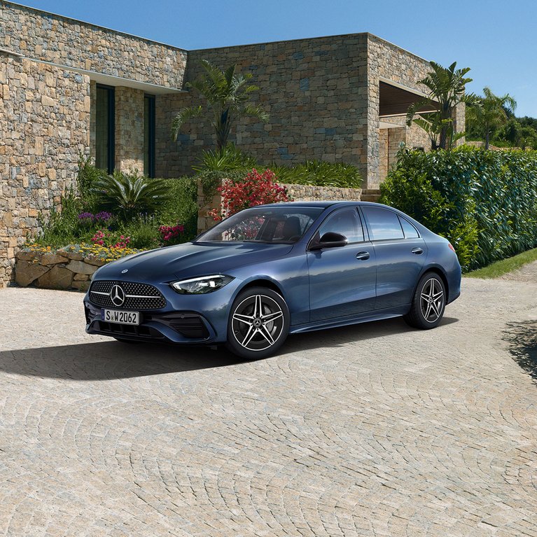Blaue Mercedes-Benz C-Klasse Limousine steht vor einer modernen Steinvilla – jetzt im Sommer 2025 zu attraktiven Leasingkonditionen sichern.