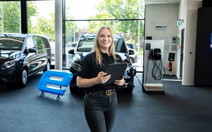 Mitarbeiterin im Autohaus von S&G mit Tablet zwischen Mercedes-Benz Fahrzeugen – Symbol für attraktive Benefits wie 30 Tage Urlaub