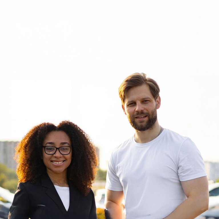 Zwei Personen nutzen ein Tablet zur digitalen Fahrzeugsuche auf einem Autohaus-Gelände.