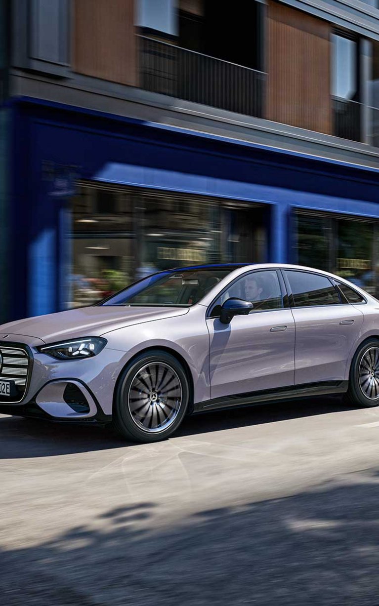 Die neue vollelektrische Mercedes-Benz C-Klasse fährt durch eine moderne Innenstadt und kombiniert elegantes Design mit innovativer Elektromobilität.