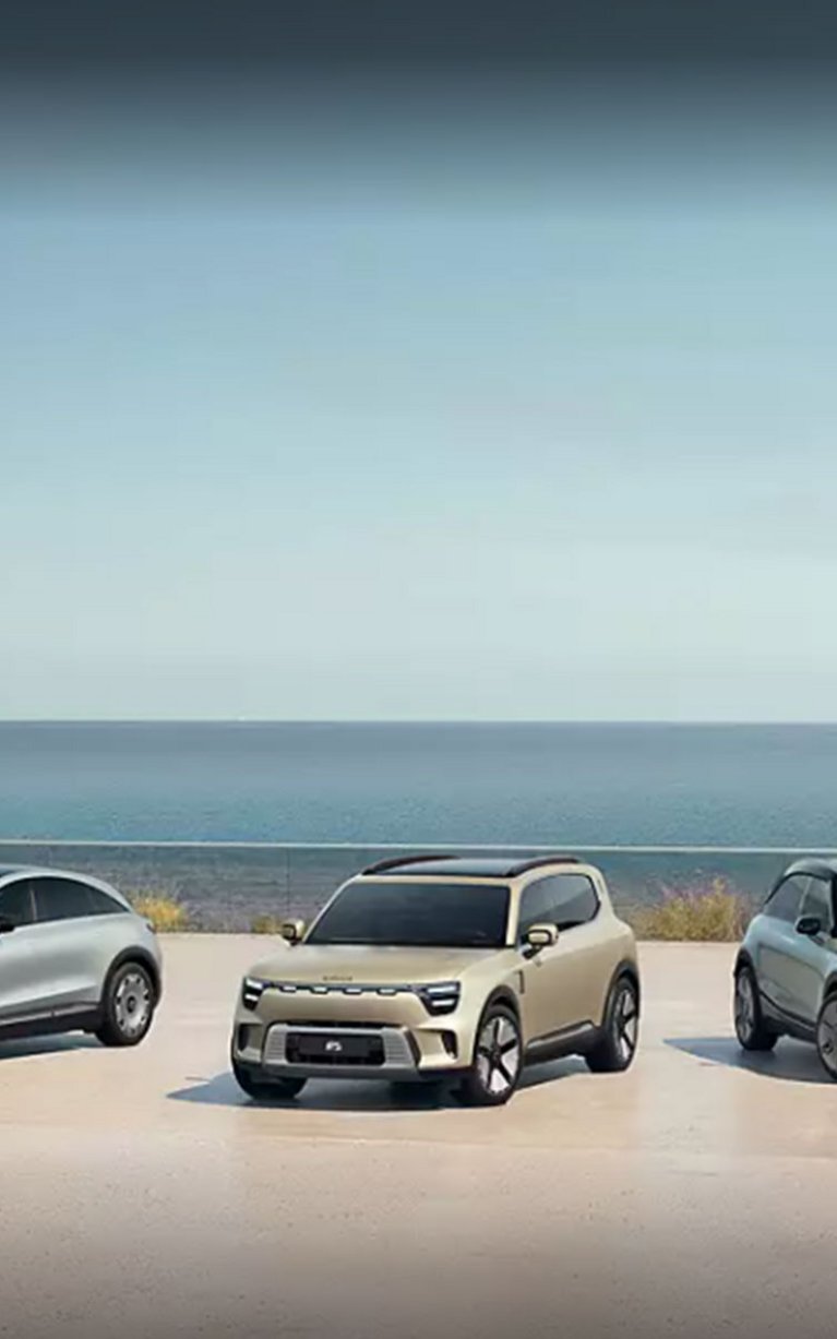 Drei vollelektrische smart-Modelle stehen nebeneinander auf einer modernen Küstenplattform mit Blick auf das Meer – futuristisches Design trifft nachhaltige Mobilität.