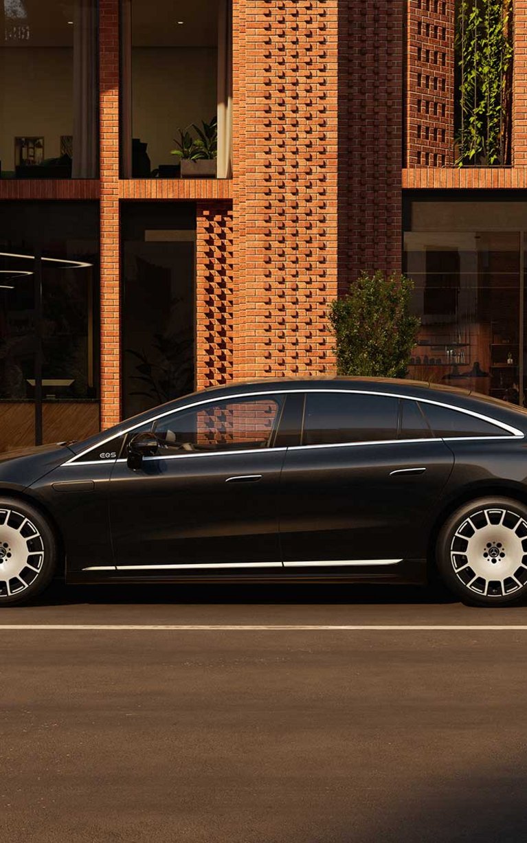 Der neue Mercedes-Benz EQS seitenansicht, schwarz vor einem modernen Haus.