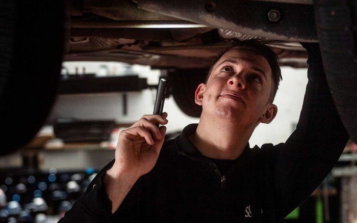 Werkstattmitarbeiter von S&G bei der Fahrzeugprüfung unter der Hebebühne – steht für sichere Zukunft und betriebliche Altersvorsorge