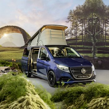 Ein blauer Mercedes-Benz Marco Polo mit geöffnetem Aufstelldach steht inmitten einer idyllischen Landschaft. Campingstühle und Tisch sind aufgebaut – Symbol für Reisen, Abenteuer und Flexibilität mit Mercedes-Benz Rent bei S&G.