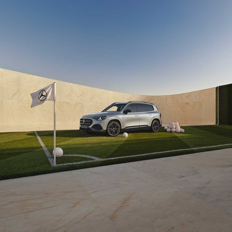 Silberner Mercedes-Benz GLB auf einem Golfplatz vor moderner Architektur mit Mercedes-Benz Fahne im Vordergrund. Das Motiv bewirbt die Mercedes-Benz Eintauschprämie bei S&G.