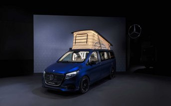 Blauer Mercedes-Benz Marco Polo mit geöffnetem und beleuchtetem Aufstelldach in einer dunklen Präsentationshalle.