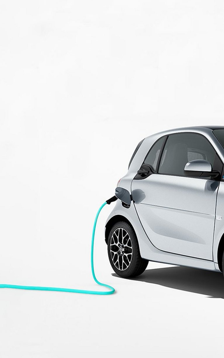 Werbebild für den smart Gebrauchtwagen-Deal des Autohauses S&G mit einem silbernen smart EQ Modell, das an einem Ladekabel zum elektrischen Aufladen angeschlossen ist. Das Angebot bewirbt die günstige Finanzierung der smart EQ Modelle.