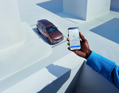 Ein Mann hält sein Smartphone an ein Fenster. Im Hintergrund ist ein Mercedes-Benz zu sehen. Es werden die Digitalen Extras von Mercedes-Benz beworben.