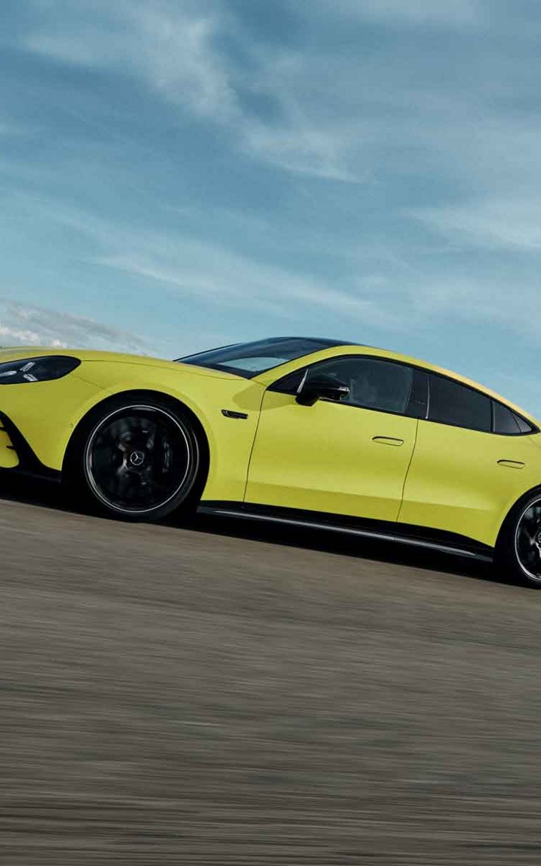 Gelber Mercedes-AMG GT 4-Türer Coupé bei dynamischer Fahrt auf einer Rennstrecke.