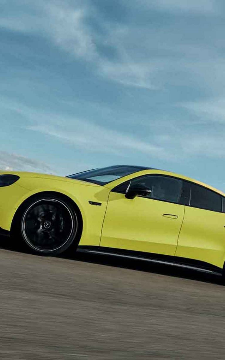 Gelber Mercedes-AMG GT 4-Türer Coupé bei dynamischer Fahrt auf einer Rennstrecke.