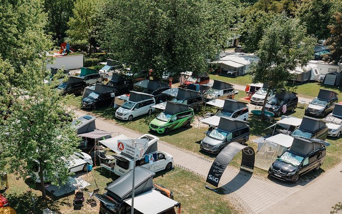 Luftaufnahme des Campingplatzes beim S&G V-Klasse Marco Polo Event 2025: Zahlreiche Mercedes-Benz Marco Polo Fahrzeuge stehen dicht nebeneinander auf Parzellen, zwischen Bäumen und Sonnensegeln – lebendige Camping-Atmosphäre bei sommerlichem Wetter.