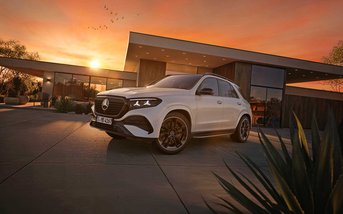 Weißer Mercedes-Benz GLE SUV vor modernem Gebäude bei Sonnenuntergang.