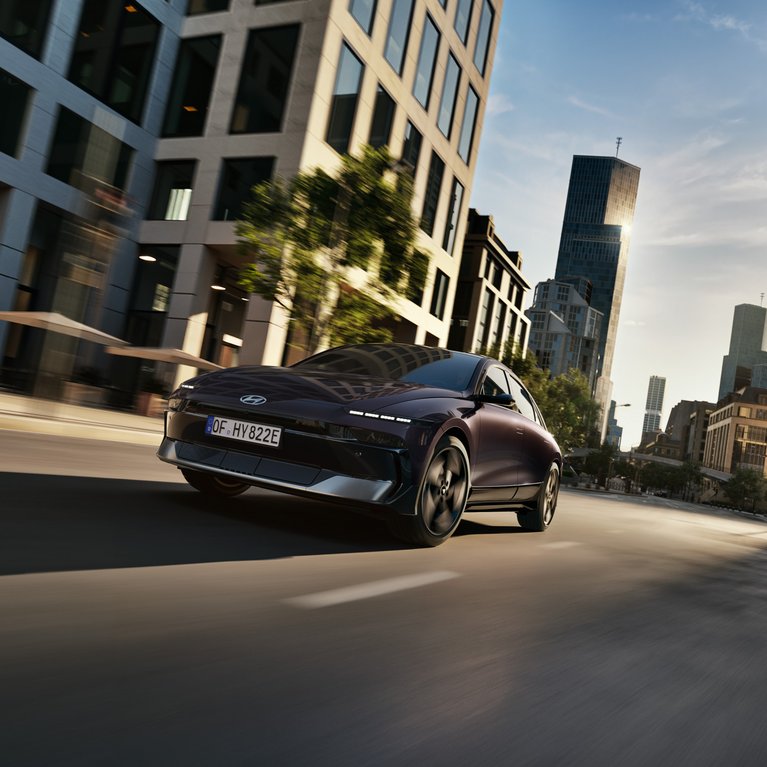 Dunkler Hyundai fährt dynamisch durch eine moderne Innenstadt zwischen hohen Gebäuden bei Abendlicht – Symbolbild für attraktive Hyundai Angebote bei S&G.
