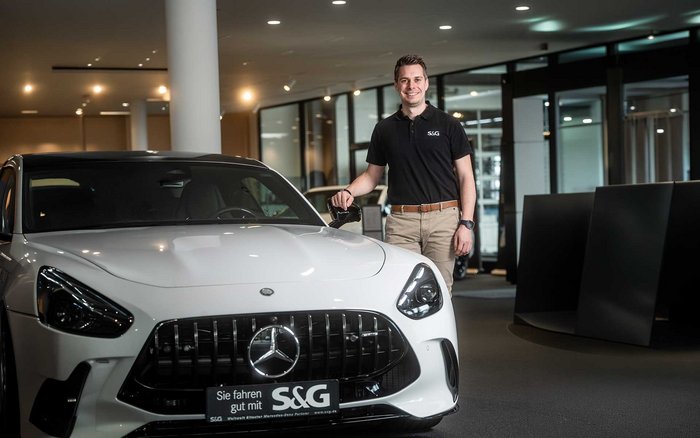 S&G Mitarbeiter im Showroom neben einem Mercedes-Benz Fahrzeug – steht für exklusive Mitarbeiterrabatte auf Fahrzeuge und Services