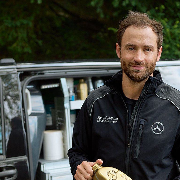 Mercedes-Benz Mobile Service Techniker von S&G Karlsruhe-Hagsfeld vor Servicefahrzeug bei der Arbeit mit Ersatzteil in der Hand.