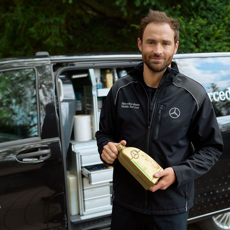 Mercedes-Benz Mobile Service Techniker von S&G Karlsruhe-Hagsfeld vor Servicefahrzeug bei der Arbeit mit Ersatzteil in der Hand.