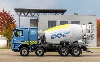 Blauer Mercedes-Benz eArocs 400 Betonmischer mit vollelektrischem Antrieb auf einem Betriebsgelände vor modernem Firmengebäude. Der elektrische Baustellen-Lkw steht für effizienten und lokal CO₂-neutralen Einsatz im Bauverkehr.
