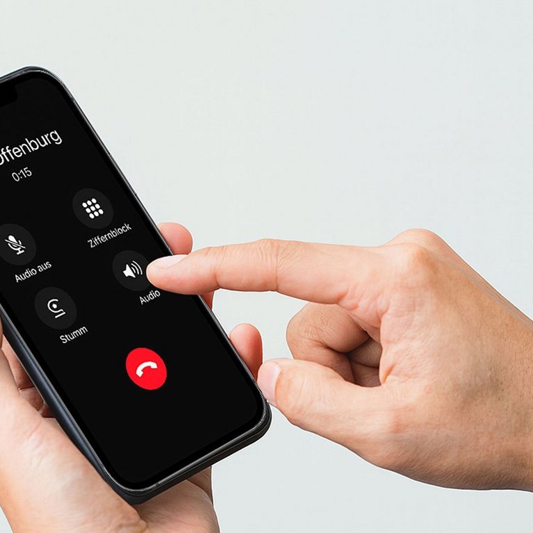 Junger Mann mit Smartphone und grauer Hintergrund im Hintergrund – Symbolbild für SmartOffice in Offenburg, bei dem Kundenanrufe sofort digital entgegengenommen werden.
