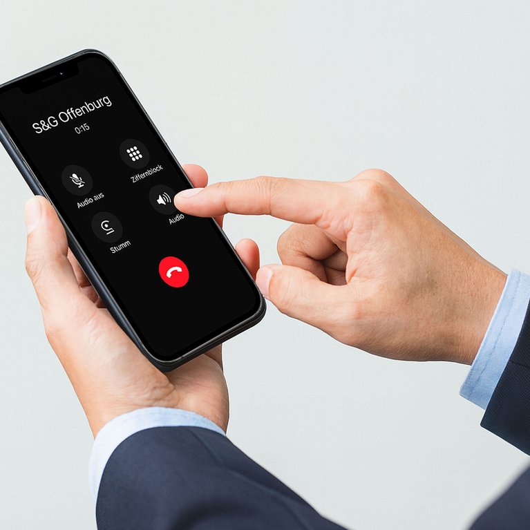 Junger Mann mit Smartphone und grauer Hintergrund im Hintergrund – Symbolbild für SmartOffice in Offenburg, bei dem Kundenanrufe sofort digital entgegengenommen werden.